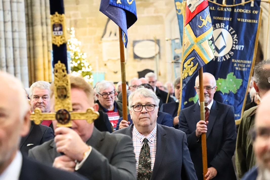 A procession of Freemasons carrying banners walks into the cathedral