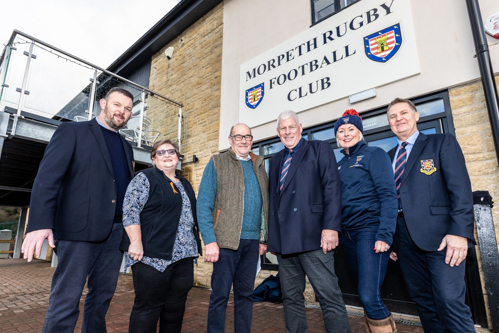 A group of people stood in front of the Rugby Club doors.