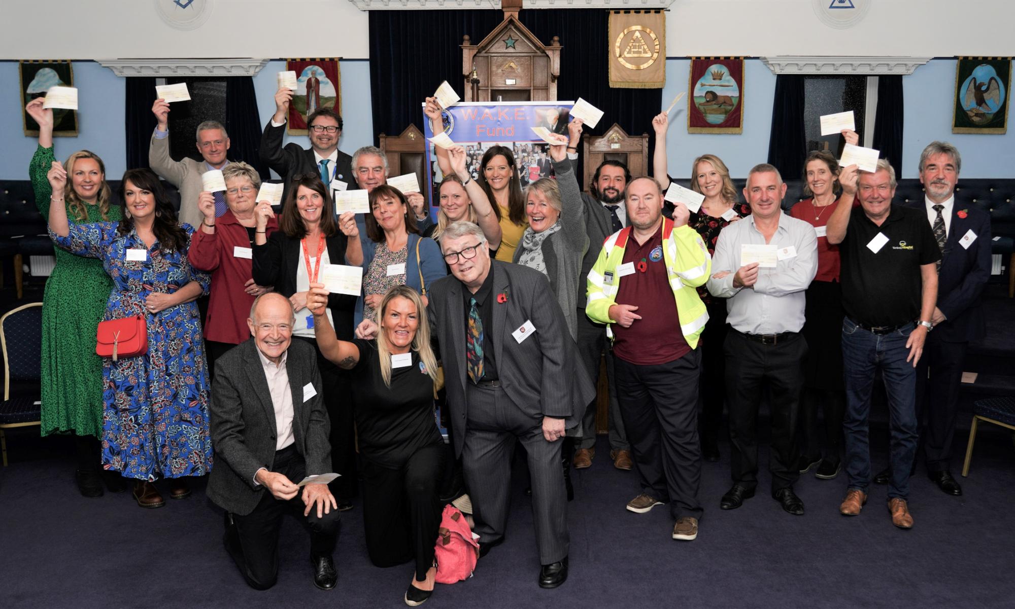 A group of people holding cheques and smiling to the camera