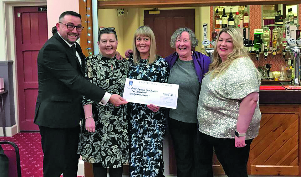 A group of people holding a giant cheque and smiling to the camera