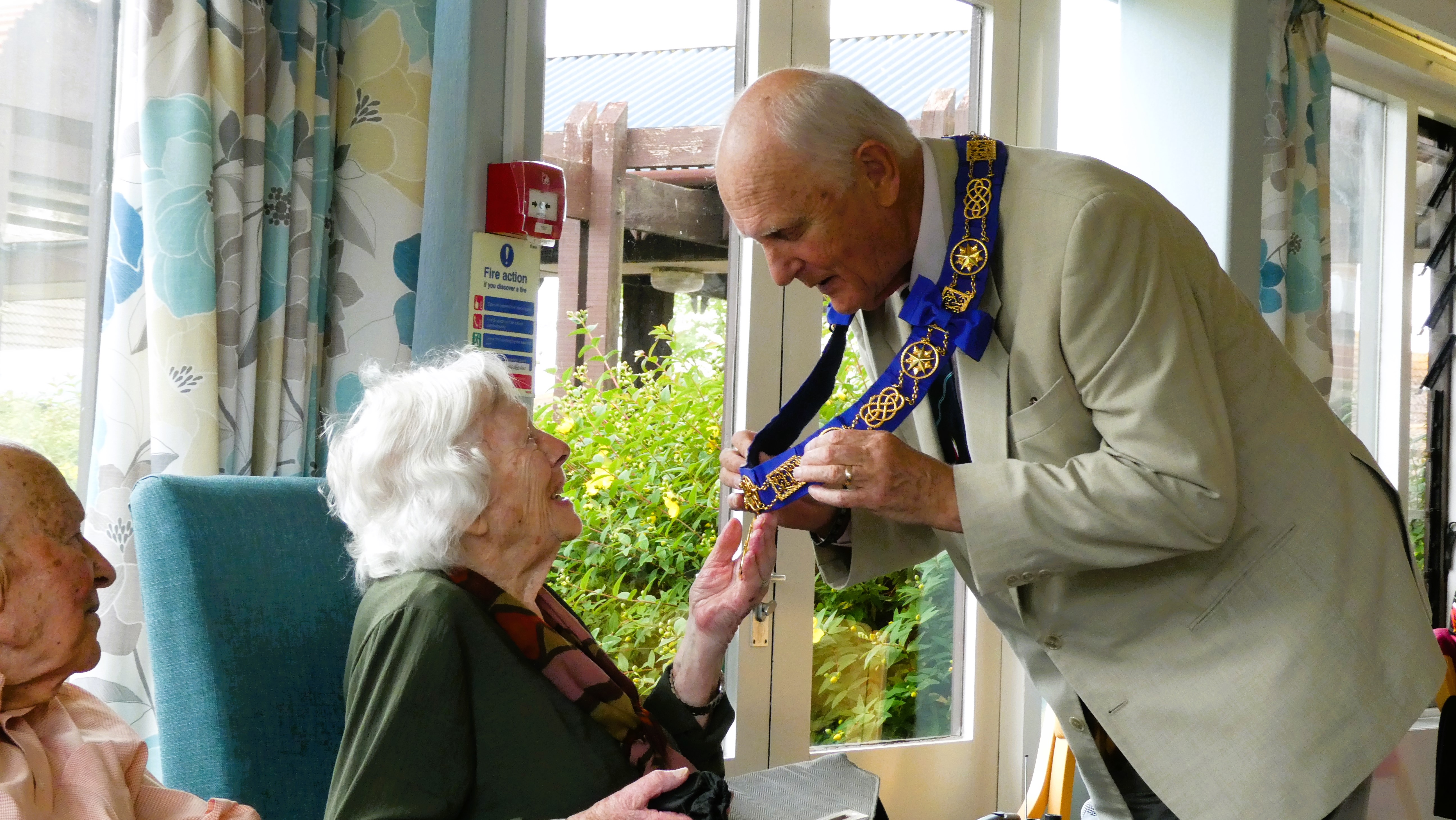 The photograph shows the Provincial Grand Master, Stephen James explaining his chain of office at a Dorset Blind Association presentation afternoon in Weymouth. 