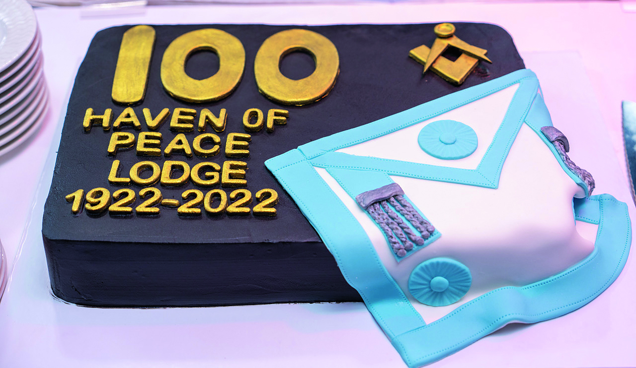 A customblack cake with fondant writing that read '100 Haven of Peace Lodge 1922-2022'