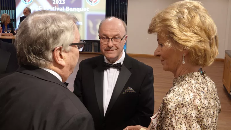 The Countess of of Arron, an older women with short hair speaking with two men. All are in formal evening wear.