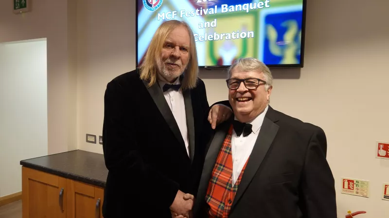 Pianist Rick Wakeman shaking hands with another man. Both are in formal wear.