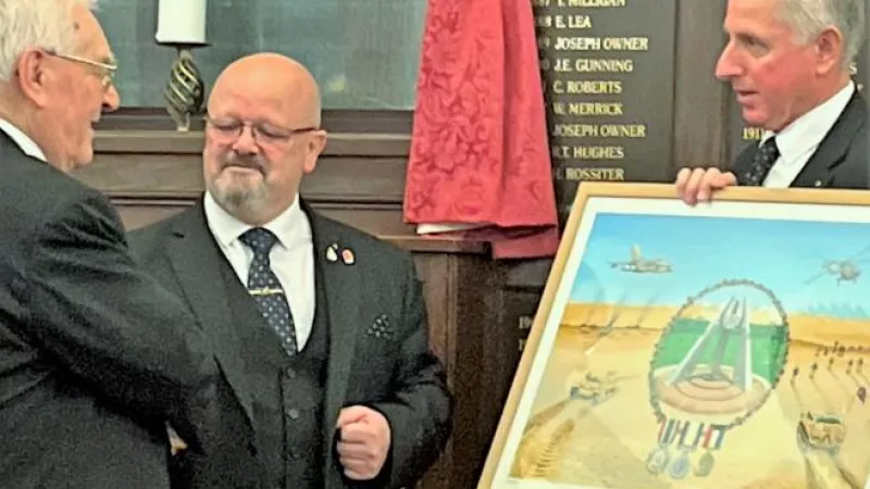 Three men, two shaking hands and the other is holding a painting